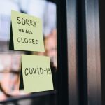 Fotografia de um vidro com dois posts-its que dizem "Sorry we are closed" e "COVID-19"